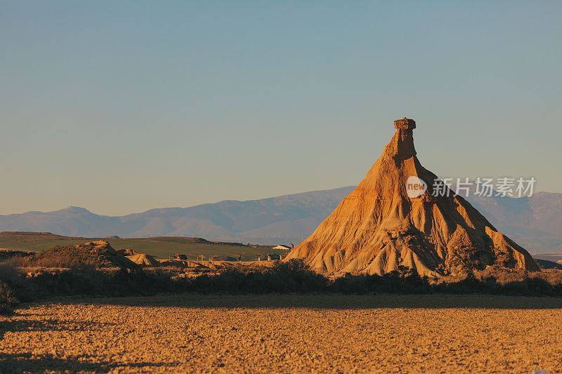 a rock formation in the desert with mountains in the background
